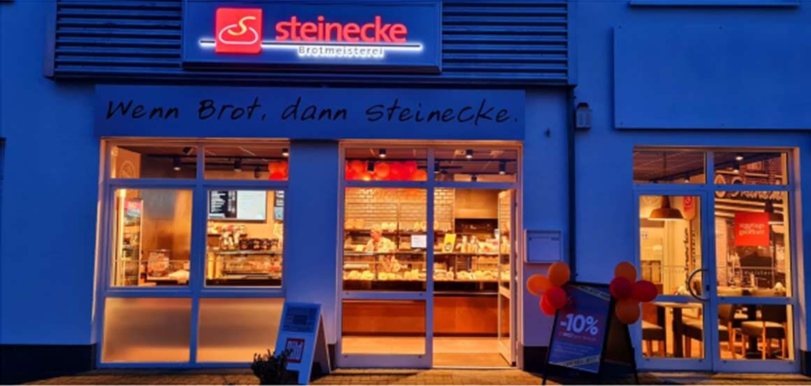 Beleuchtete Bäckerei mit Café an der Hehlinger Straße am Abend