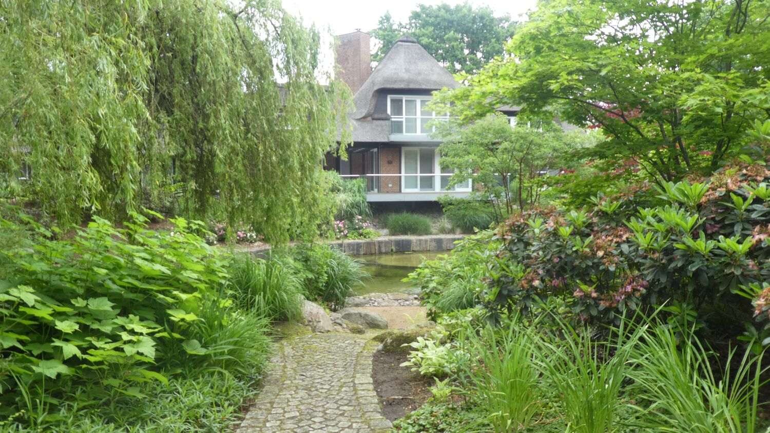 Teich im Park mit Trauerweide und Villa im Hintergrund