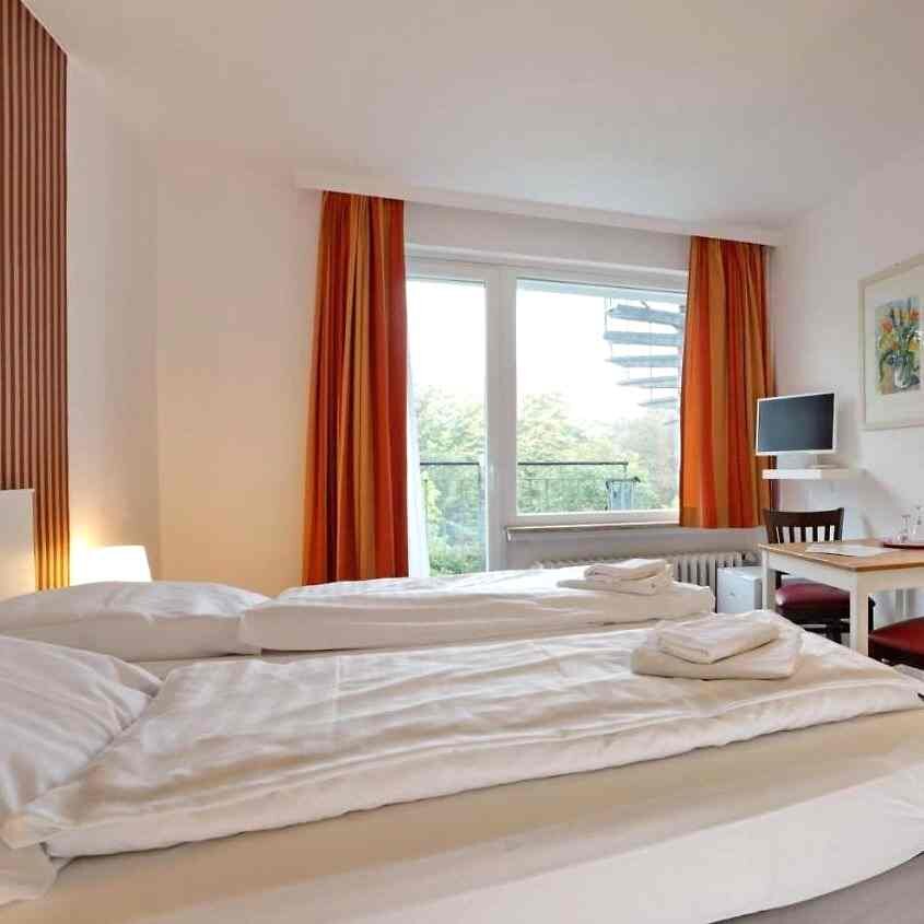 Hotelzimmer mit Doppelbett und Fenster ins Grüne