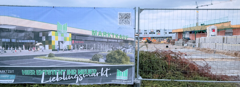 Bauzaunbanner vor dem Rohbau des neuen Marktkauf