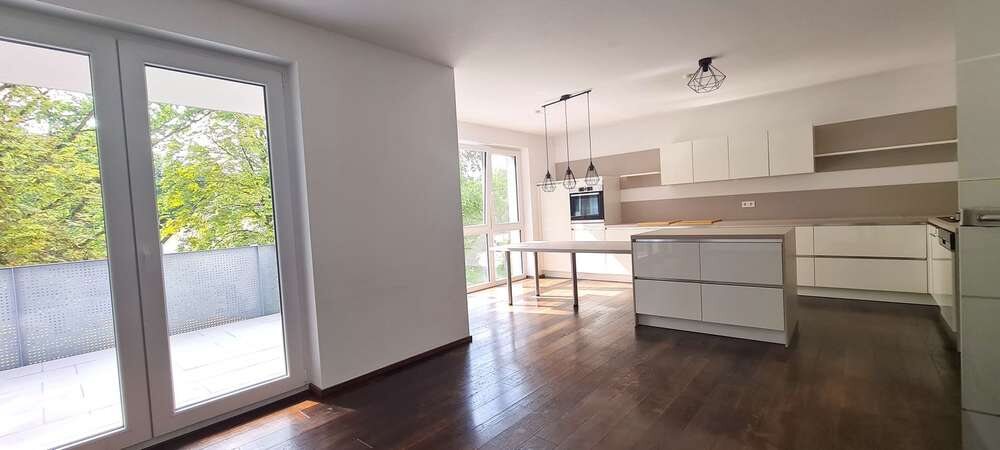 Offene Küche mit Kochinsel und Zugang zum Balkon
